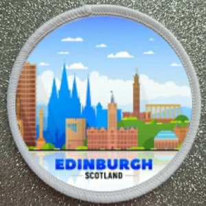 May include: A circular patch with a detailed illustration of the Edinburgh skyline, set against a blue sky with clouds. The text "EDINBURGH SCOTLAND" is displayed in blue at the bottom. The patch has a white border.