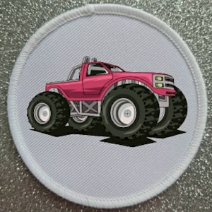 Könnte beinhalten: Ein rosafarbener Monstertruck mit großen schwarzen Reifen auf weißem Hintergrund. Der Truck hat einen schwarzen Kühlergrill und schwarze Scheinwerfer.