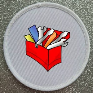 Può includere: Un cerotto rotondo bianco con una cassetta degli attrezzi rossa piena di vari strumenti, tra cui una chiave inglese, un cacciavite e un martello. Gli strumenti sono rappresentati in uno stile cartone animato.