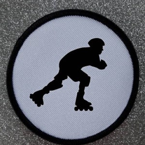 May include: Black and white silhouette of a roller skater on a white circular patch.