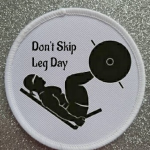 May include: White round patch with black text and a silhouette of a person doing a leg press exercise. The text reads "Don't Skip Leg Day".