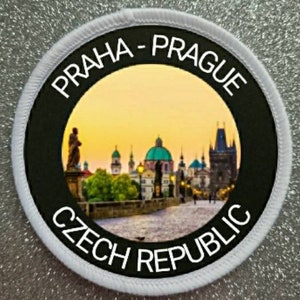Könnte beinhalten: Ein weißer runder Patch mit schwarzem Text und einem schwarzen Kreis in der Mitte. Der Text lautet "PRAHA - PRAGUE CZECH REPUBLIC". Der Kreis enthält ein Foto der Karlsbrücke in Prag, Tschechien.