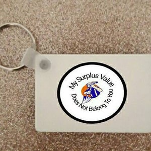 May include: White keychain with a black circle containing the text "My Surplus Value Does Not Belong To You" and a cartoon image of a person holding a tool.