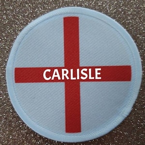 Puede incluir: Parche redondo blanco con una cruz roja y la palabra "CARLISLE" en el centro.