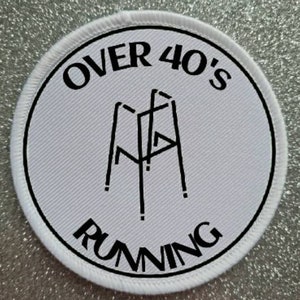 May include: White round patch with black text and a black illustration of a walking frame. The text reads "Over 40's Running".