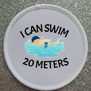 May include: White round patch with black text that reads "I can swim 20 meters". A cartoon illustration of a person swimming in a pool is in the center of the patch.