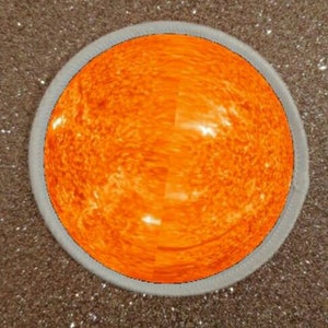 Pode incluir: Close-up de uma esfera laranja brilhante com uma superfície texturizada, cercada por um anel branco.