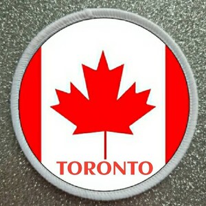 May include: A white and red circular patch with a red maple leaf and the word "TORONTO" in red letters.