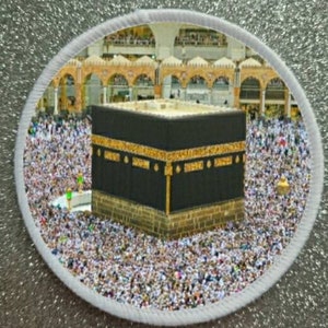 Puede incluir: Un gran edificio de forma cúbica negro con adornos dorados, rodeado de una multitud de personas. El edificio se encuentra sobre un fondo de una estructura blanca y dorada con arcos.