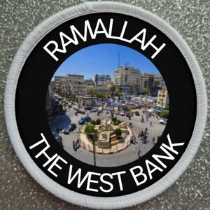 May include: A white and black circular patch with the text "Ramallah The West Bank" in white lettering on a black background. The centre of the patch features a fisheye lens view of a city street scene.