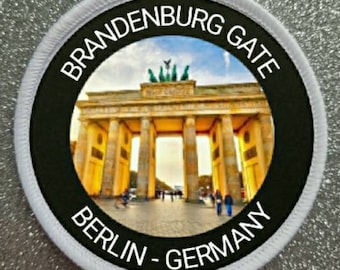 Puede incluir: Un parche circular blanco y negro con el texto "Brandenburg Gate Berlin - Germany" alrededor de una foto de la Puerta de Brandeburgo en Berlín, Alemania.