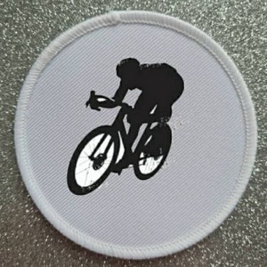 May include: White round patch with a black silhouette of a cyclist riding a bicycle.