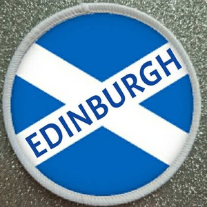 May include: A white and blue round patch with the text "EDINBURGH" in blue letters on a white diagonal cross against a blue background. The patch has a white border.