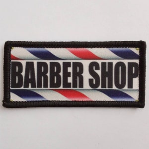 May include: A black and white barber shop patch with red and blue stripes. The patch says "Barber Shop" in black letters.