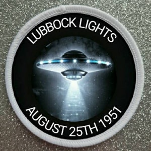 Puede incluir: Un parche circular blanco con texto negro y una imagen en blanco y negro de un platillo volante. El texto dice "Lubbock Lights August 25th 1951".