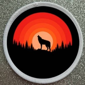 Könnte beinhalten: Eine schwarze Silhouette eines Wolfes, der zum Mond heult, vor einem roten und orangen Sonnenuntergang. Der Wolf steht auf einem Hügel mit Bäumen im Hintergrund.