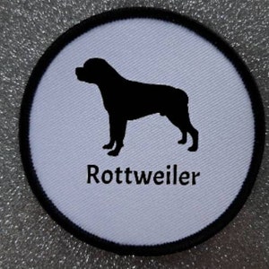 Puede incluir: Parche redondo blanco con una silueta negra de un Rottweiler y el texto "Rottweiler" en negro.