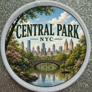 May include: Round patch featuring a scenic illustration of Central Park in New York City. The image includes a bridge, boats on the water, and the city skyline under a blue sky with clouds. The text "CENTRAL PARK NYC" is displayed in green.