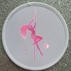 Peut inclure: Un patch rond blanc avec une silhouette rose d'une personne sur un poteau. La silhouette est de style aquarelle avec des nuances de rose et de blanc.