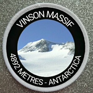 May include: White round patch with black text and a photo of a snow-capped mountain. The text reads "Vinson Massif 4892 Metres - Antarctica".