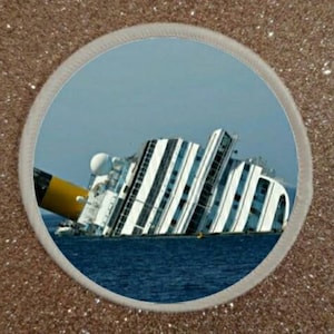 May include: A large white cruise ship is partially submerged in the water. The ship is tilted on its side, with the bow facing the sky. The water is a deep blue, and the sky is a light blue.