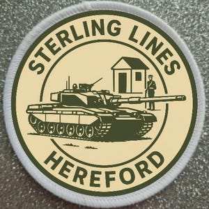 May include: A round patch with a cream-coloured background and a green border. The patch depicts a tank, a small building, and a soldier. The words "STERLING LINES HEREFORD" are printed around the edge in green.