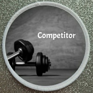 May include: A black and white image of a dumbbell with the word "Competitor" written in white text on a grey background.