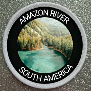 May include: White round patch with black border and text "AMAZON RIVER SOUTH AMERICA". The patch features a photo of a river flowing through a lush green forest.