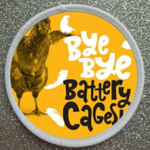 May include: A white round patch with a yellow background. The patch features a cartoon chicken with a white feather in its beak. The text "Bye Bye Battery Cages!" is written in white and black letters.