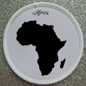 Peut inclure: Un écusson en tissu blanc avec un contour noir du continent africain. Le mot "Afrique" est écrit en cursive noire au-dessus du continent.