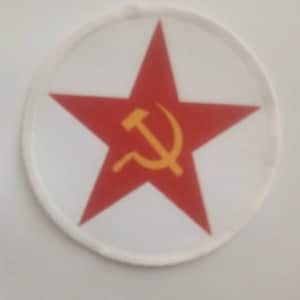 Könnte beinhalten: Ein roter Stern mit einem gelben Hammer und Sichel darin, auf einem weißen runden Patch.