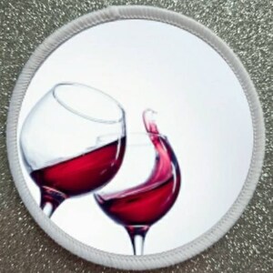 May include: Two wine glasses clinking together, one filled with red wine and the other with red wine that is splashing out of the glass.