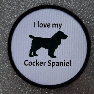 May include: White round patch with black stitching and the text "I love my Cocker Spaniel" with a black silhouette of a cocker spaniel dog.