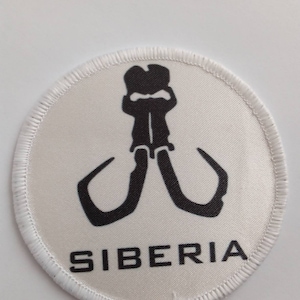 May include: White circular patch with a black embroidered image of a mammoth with the word "SIBERIA" underneath.