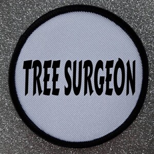 May include: White round patch with a black border and the text "TREE SURGEON" in bold black letters.