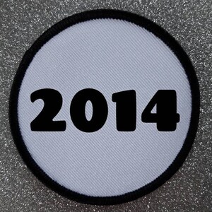 May include: White round patch with a black border and the year 2014 printed in black.