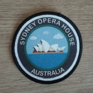 Op de afbeelding: Een ronde zwarte en witte patch met de tekst "Sydney Opera House Australia" en een afbeelding van het Sydney Opera House.