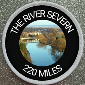 Puede incluir: Un parche redondo blanco y negro con el texto "The River Severn 220 Miles" en blanco. El parche presenta una foto de un río con árboles y un pueblo en el fondo.
