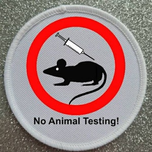 May include: White round patch with a red circle and a black silhouette of a mouse with a syringe. The text "No Animal Testing!" is printed below the circle.
