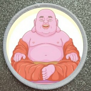 May include: A round, white patch with a gray border features a cartoon illustration of a pink Buddha sitting cross-legged in a red robe.