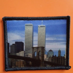 Könnte beinhalten: Ein gestickter Aufnäher in Schwarzweiß, der eine Stadtlandschaft mit der Brooklyn Bridge und den Zwillingstürmen im Hintergrund zeigt.