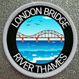 Peut inclure: Un écusson circulaire blanc avec du texte noir et une image colorée du pont de Londres sur la Tamise. Le texte indique "London Bridge River Thames".