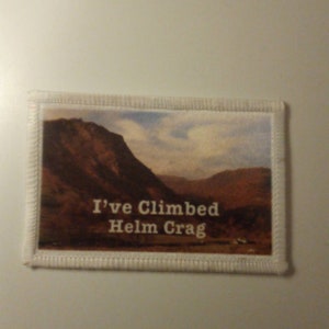 May include: White fabric patch with a photo of a mountain range and the text "I've Climbed Helm Crag".