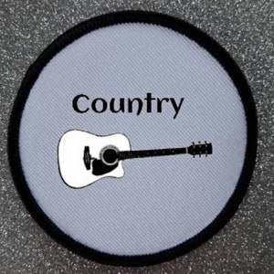 Puede incluir: Parche de tela blanca con costuras negras alrededor del borde. El parche presenta una silueta negra de una guitarra acústica y la palabra "Country" en texto negro.