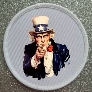 Puede incluir: Un parche redondo de tela azul con un borde blanco. El parche presenta una imagen vintage del Tío Sam, con un sombrero rojo, blanco y azul, apuntando con el dedo hacia el espectador. El texto "I Want You For U.S. Army" está impreso debajo de la imagen.