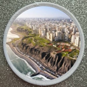 May include: An aerial view of a coastal city with a cliffside and a beach. The city is built on a hillside and has many buildings. The beach is sandy and has waves crashing on the shore.