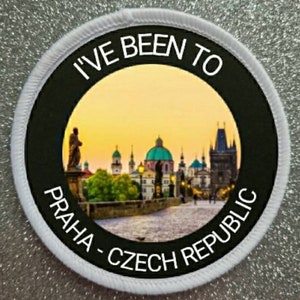 May include: White round patch with black border and text "I've Been To Praha - Czech Republic". The center features a photo of Prague's Charles Bridge at sunset.