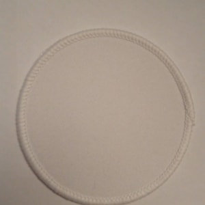 May include: White round fabric patch with a stitched edge.