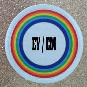May include: White round patch with a rainbow border and the text "EY/EM" in black letters on a white background.