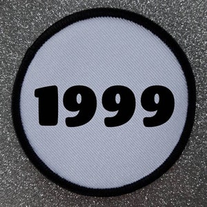 Può includere: Toppa rotonda bianca con cuciture nere attorno al bordo. La toppa ha l'anno 1999 stampato in nero.